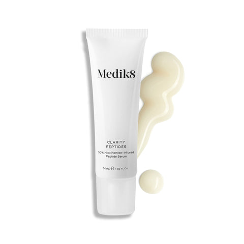 A tube of Medik8 Clarity Peptides™ niacinamide serum on a white background, with a bit of cream spilled beside it, ideal for nurturing blemish-prone skin.