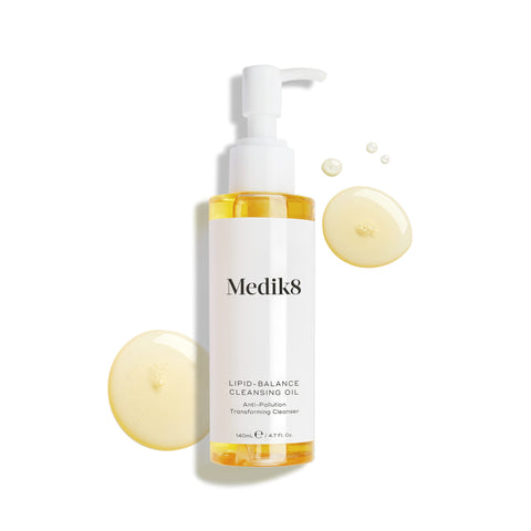 A bottle of Lipid-Balance Cleansing Oil™ by Medik8, surrounded by oil droplets. The 140ml (4.7 fl. oz) bottle with a pump features innovative anti-pollution technology, effortlessly removing makeup while nourishing your skin.
