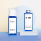 Two Medik8 Press & Clear bottles sit on a blue and beige background, featuring one with a pump for BHA toning and another with a screw cap, both enriched with Salicylic Acid.