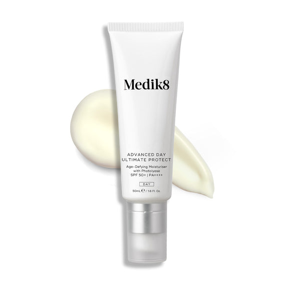 A white tube of Medik8's Advanced Day Ultimate Protect™ moisturizer SPF 50+, featuring DNA repair enzymes, sits elegantly against a swirled cream backdrop, promising a non-comedogenic finish.