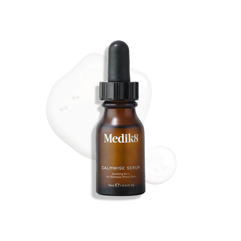 A brown dropper bottle labeled "Medik8" rests on a clear liquid spill against a white backdrop. Named "Calmwise™ Serum," this anti-redness formula, featuring teprenone, provides soothing relief for sensitive skin.