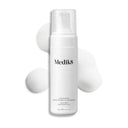 A white Medik8 Calmwise™ Soothing Cleanser bottle, chlorophyll-infused for enhanced care, features a pump top. Nestled amid gentle foam on a pristine white backdrop, it's perfect for soothing compromised skin.