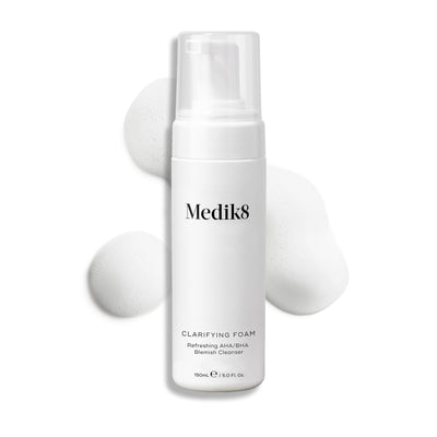 A 150ml bottle of Medik8's Clarifying Foam™, enriched with refreshing AHAs and BHAs, with foam bubbles elegantly surrounding it.