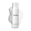 A white bottle of Medik8's Micellar Mousse™, featuring micellar cleansing technology, rests against a white foam backdrop. The label reads: "Purifying & Nourishing, Effortless Rinse-Off Cleanser." Ideal for makeup removal, the bottle holds 150 ml (5 fl oz).