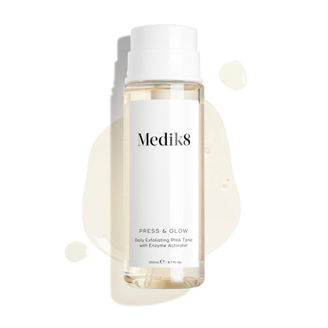 A bottle of Medik8's Press & Glow® Daily Exfoliating PHA Tonic, featuring a white label against a white background, highlights its skin-glowing properties with polyhydroxy acid, elegantly scattered around.