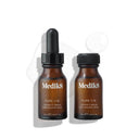 Two brown bottles of Medik8 Pure C15™ featuring a black dropper rest on a white background. A small drop of the age-defying serum, known for its antioxidant protection with ascorbic acid, is visible beside them.