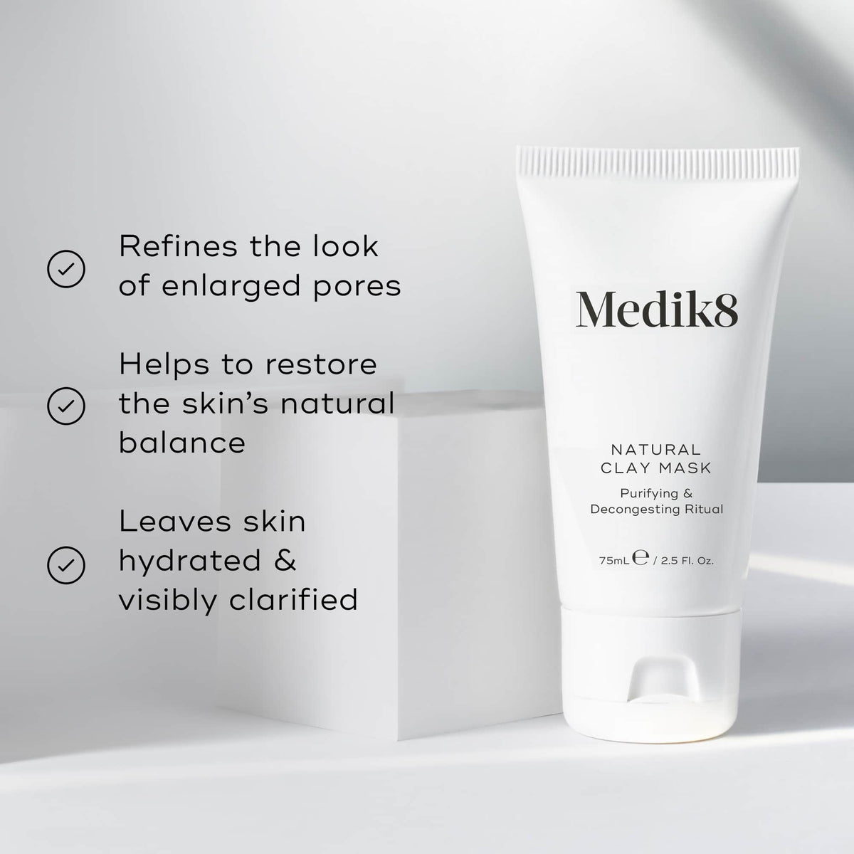 A tube of Medik8 Natural Clay Mask™, with bentonite and kaolin clay, sits on a white surface. Text emphasizes its benefits: refining pores, restoring skin balance, and hydrating the skin.