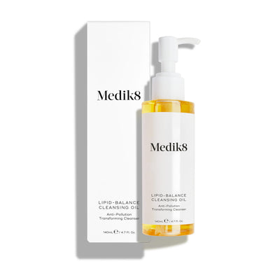 A Medik8 Lipid-Balance Cleansing Oil™ bottle with a pump top is showcased alongside its box against a plain background, featuring anti-pollution technology for effective makeup removal.