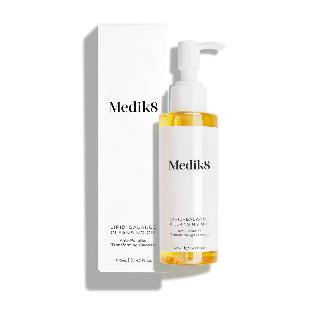 A Medik8 Lipid-Balance Cleansing Oil™ bottle with a pump top is showcased alongside its box against a plain background, featuring anti-pollution technology for effective makeup removal.
