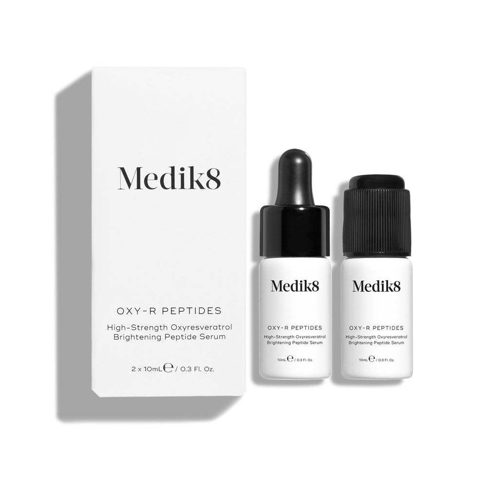 Two Medik8 serum bottles, one with a dropper cap and the other with a screw cap, are elegantly displayed beside their white box labeled "Oxy-R Peptides™" on a pristine white background. This powerful peptide serum utilizes oxyresveratrol to address dark spots.