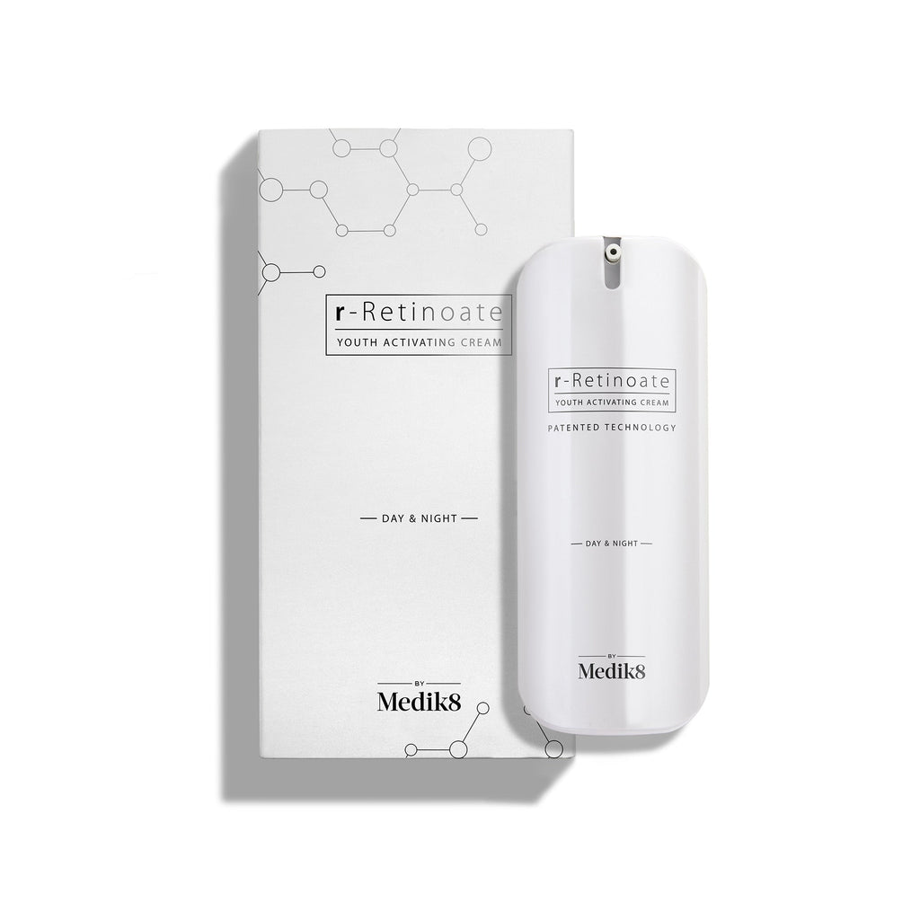 A bottle of Medik8's r-Retinoate® Day & Night, enriched with retinyl retinoate vitamin A, stands elegantly before its box. The minimalistic design features molecular graphics, mirroring its advanced anti-aging serum formula.