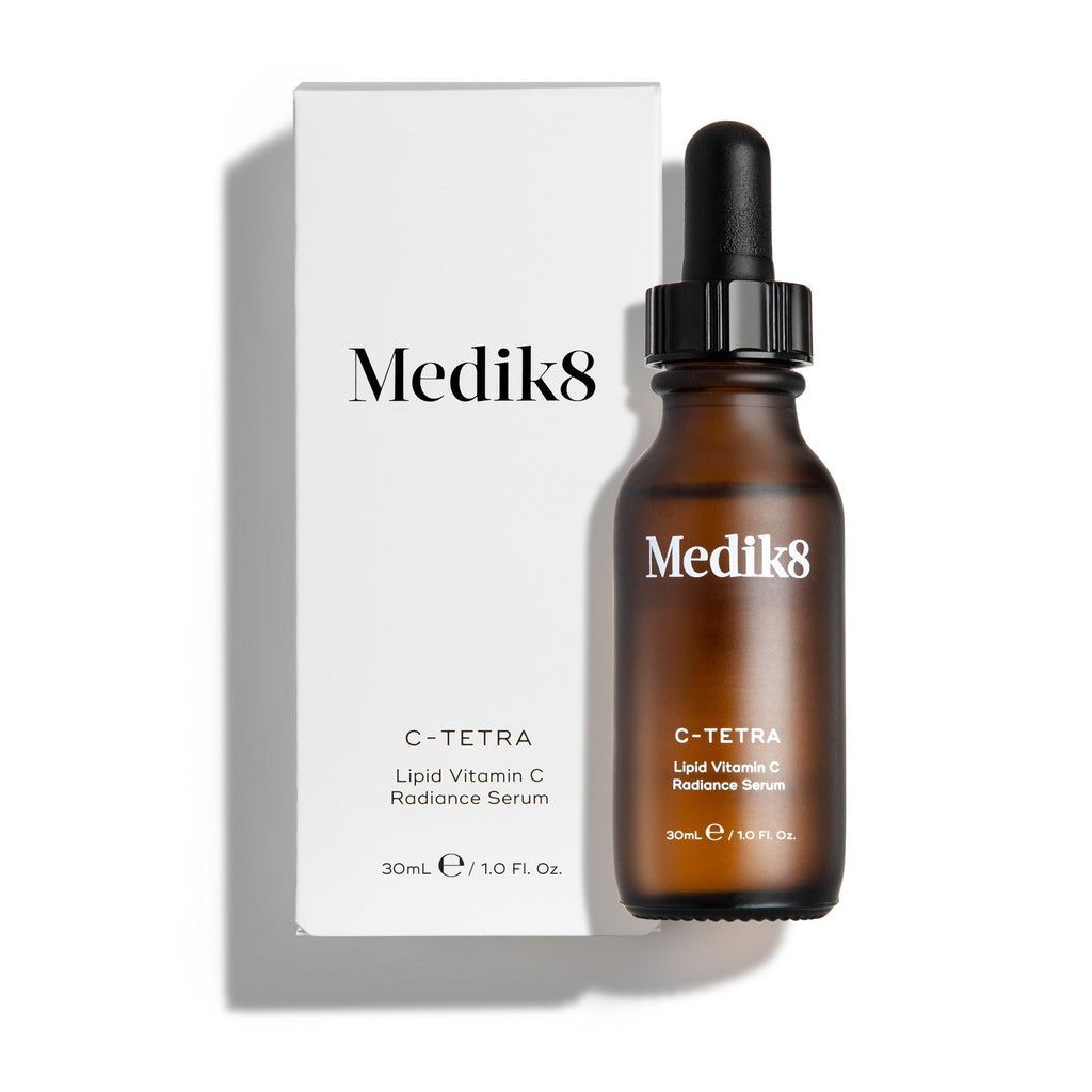 A brown glass bottle labeled with "C-Tetra®" from Medik8, renowned for its skin radiance-boosting vitamin C formula, comes with a white box featuring matching branding and product details.