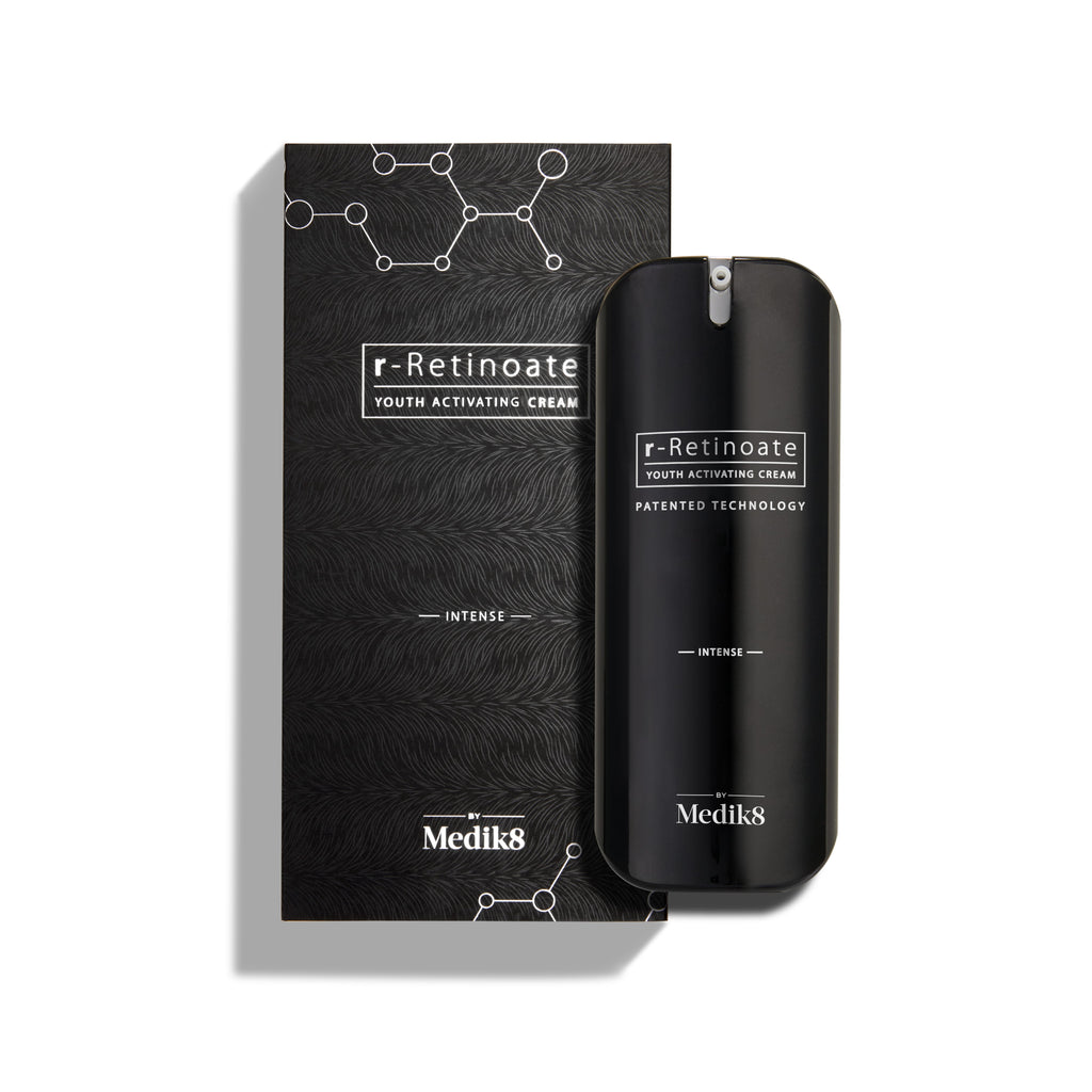 A sleek black bottle of Medik8's r-Retinoate® Intense, enriched with Vitamin A for effective wrinkle reduction, sits beside its matching box adorned with a molecular pattern and labeled "Patented Technology.