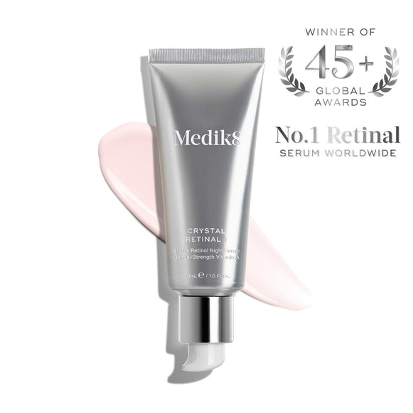A silver tube of Medik8 Crystal Retinal®, the No.1 anti-ageing serum worldwide and winner of 45+ global awards, featuring a pink cream smear.