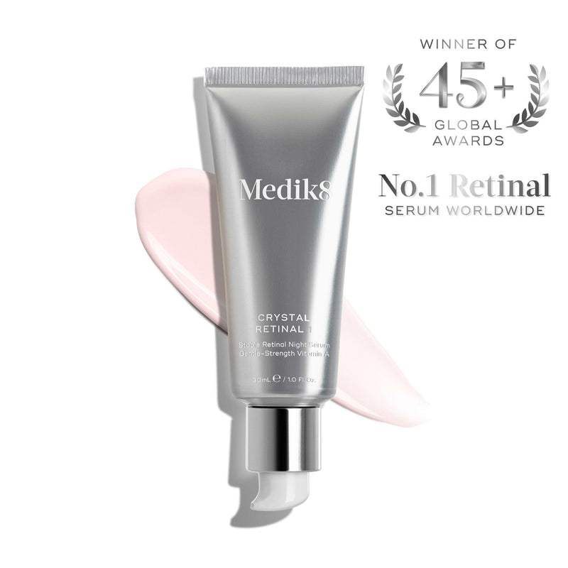 A silver tube of Medik8 Crystal Retinal®, the No.1 anti-ageing serum worldwide and winner of 45+ global awards, featuring a pink cream smear.