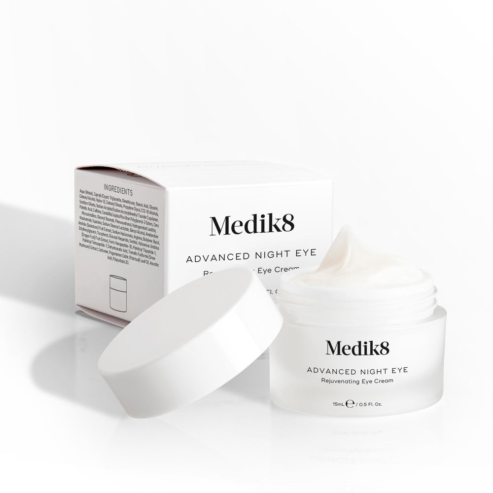 A jar of Medik8's Advanced Night Eye™, formulated with vitamin A, is open beside its box on a plain white background.