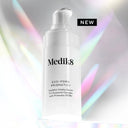 A white bottle of Medik8 Cyprus Exo-PDRN Prismatic+ serum with a pump dispenser, set against a backdrop of soft rainbow lighting.