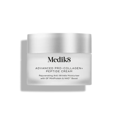 A travel-size jar of Medik8 Cyprus Advanced Pro-Collagen+ Peptide Cream with a silver lid, labeled as an anti-wrinkle collagen cream supporting skin firmness with GF MiniProtein and NAD+ boost.