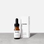 A Medik8 C-Tetra® brown dropper bottle, a vitamin C-rich antioxidant serum for skin radiance, stands by its white box on a gray surface against a light background.