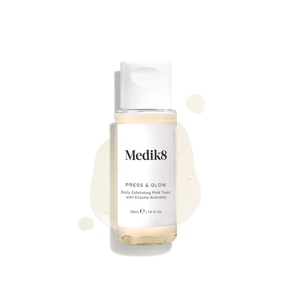A 30ml/1.0 fl. oz bottle of Medik8 Press & Glow™ (Travel Size) Daily Exfoliating PHA Tonic with Enzyme Activator for sensitive skin, featuring a light splash behind it.-13